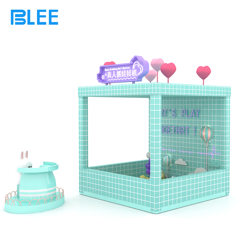 family entertainment center game Player using both hands to scoop up prizes while suspended mid-air inside the real-life claw machine.