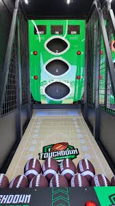 Football toss arcade game lane with three scoring targets and footballs